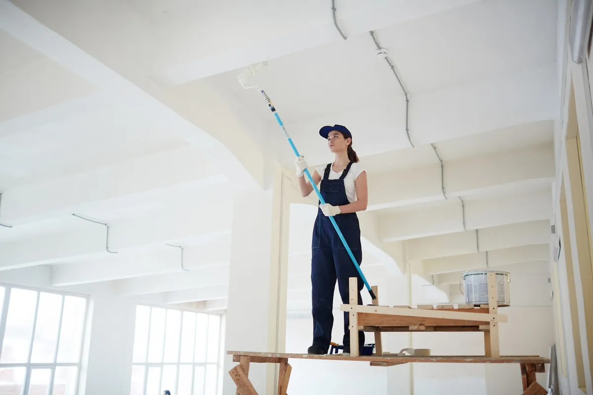 Painter on a platform rolling paint onto a commercial ceiling